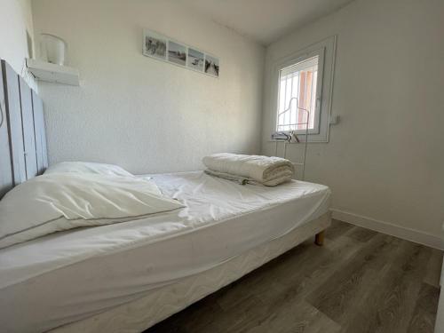un lit blanc dans une chambre avec une fenêtre dans l'établissement Confortable T2 à Sète avec vue mer, parking et WiFi - FR-1-338-111, à Sète