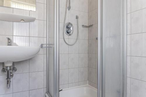 ein weißes Bad mit einer Dusche und einem Waschbecken in der Unterkunft 50152... in Carolinensiel