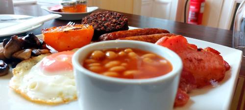 a plate of breakfast food with eggs meat and beans at The Harbour Inn in Garlieston