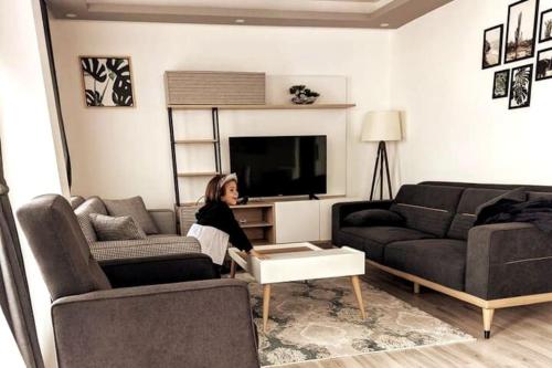 una mujer está sentada en una sala de estar en Sea Breeze Apartment, en Milas