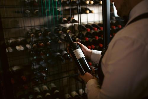 a man holding a wine bottle in front of a wine rack at Stufvenäs Gästgifveri in Söderåkra