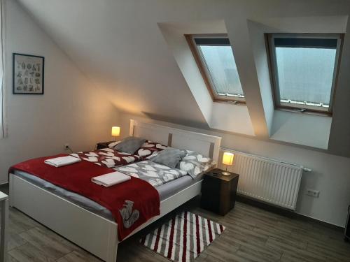 a bedroom with a bed and two windows at Patak Vendégház in Zalaegerszeg