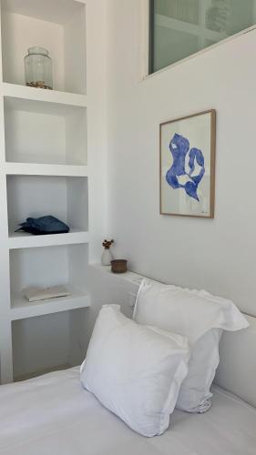 a white bedroom with white shelves and a white pillow at Hotel La Potiniere in Hyères
