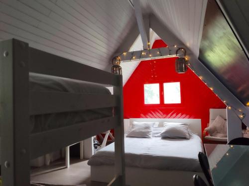 a bedroom with a red wall and two bunk beds at Résidence privée en forêt 15 min du circuit in Changé