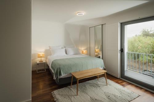 um quarto com uma cama e uma grande janela em Figueiras House Pópulo Beach em Ponta Delgada