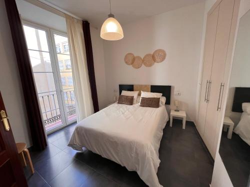 - une chambre avec un lit blanc et une grande fenêtre dans l'établissement Málaga La Bella centro histórico, à Malaga
