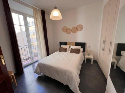 Un dormitorio con una cama blanca y una ventana grande. en Málaga La Bella centro histórico, en Málaga