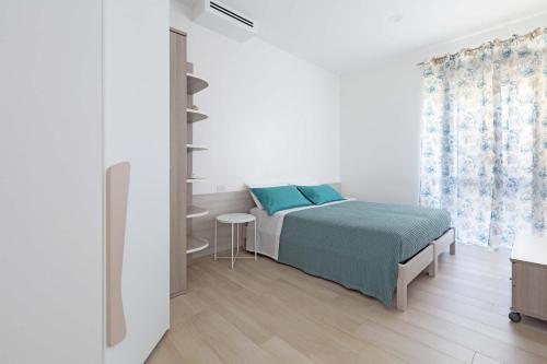 a white bedroom with a bed and a window at Appartamento Vitalba by BarbarHouse in Ginosa Marina