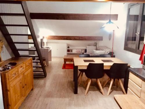 a living room with a table and chairs and a staircase at Appartement Duplex Forclaz in Chamonix-Mont-Blanc
