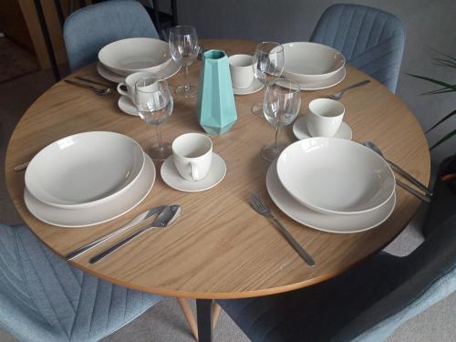 a wooden table with white plates and wine glasses at Wroclove Airport Loft in Wrocław