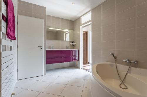 ein Badezimmer mit einer Badewanne und einem lila Schrank in der Unterkunft Paray - Maison avec jardin de 400m2 in Paray-Vieille-Poste