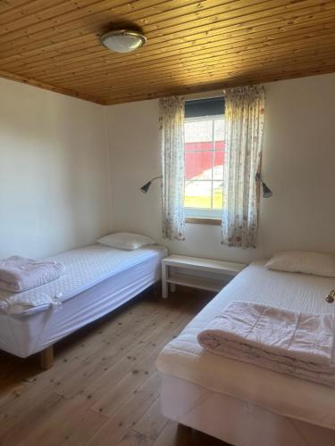 two beds in a room with a window at Svalsjöns Stugor Öland in Köpingsvik