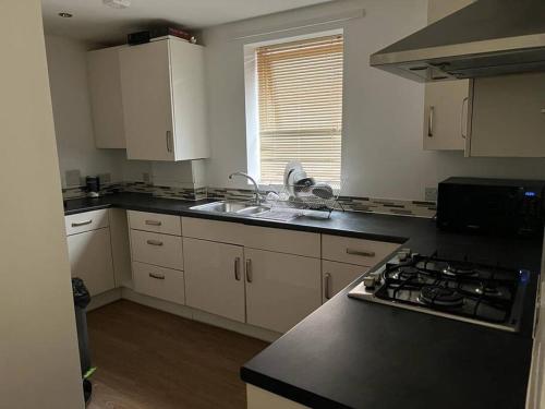 una cucina con armadi bianchi, lavandino e piano cottura di Comfy One bedroom Apartment a Londra