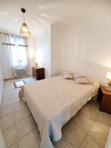 - une chambre blanche avec un grand lit et un lustre dans l'établissement Maison de vacances Gite le Margot, à Cantenac