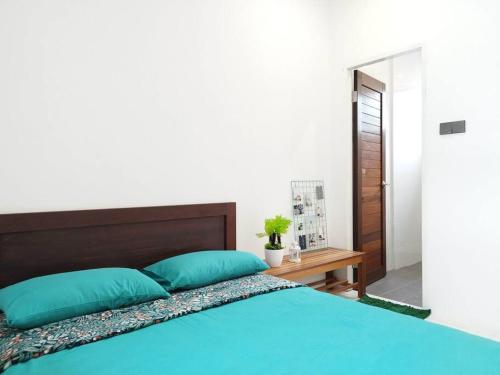 a bedroom with a bed with blue pillows and a table at Nanyang Homestay 10 pax Free Wifi & Washer-1st Floor in Sibu