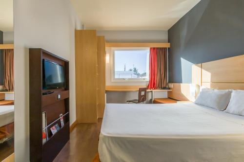 um quarto de hotel com uma cama e uma televisão em ibis Barretos em Barretos
