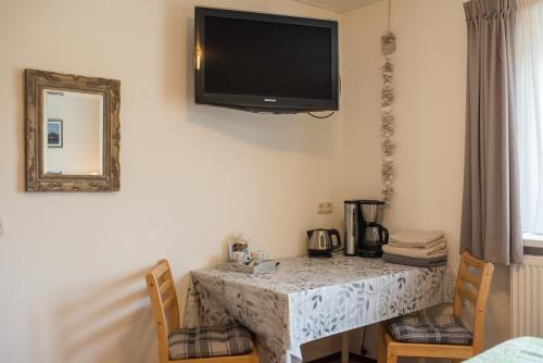 a dining room table with a television on the wall at B&B Molenaar in Buren