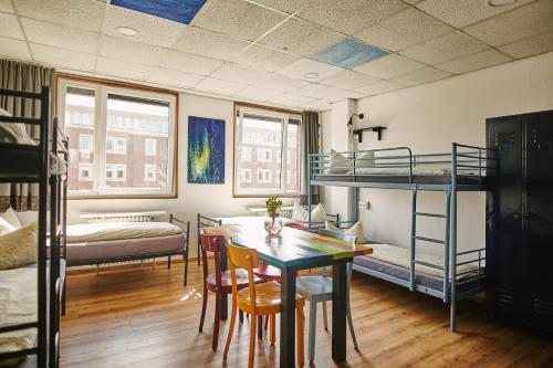 a room with bunk beds and a table and chairs at Sleep Station Hostel in Münster