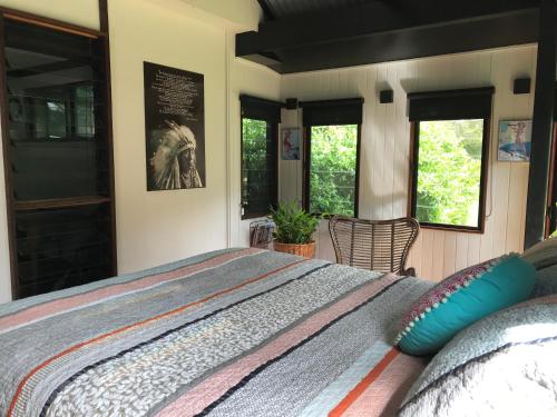 a bedroom with a bed and two windows at PK illusions in Maleny