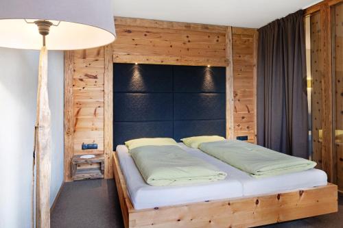 Cama en habitación con pared de madera en Angerle Alm Apt Similde B, en Carezza al Lago