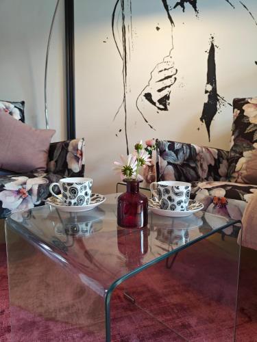 a glass coffee table with two tea cups on it at ArtRoom Boarding Apartment in Bissendorf