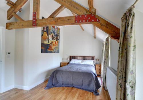 um quarto com uma cama num quarto com vigas de madeira em Clematis Cottage em Gilling East
