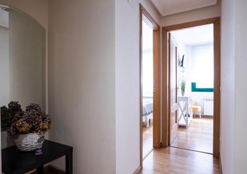 a hallway with a vase of flowers on a table and a mirror at Apartamento céntrico con wifi y parking de coche tamaño medio in Cangas de Onís