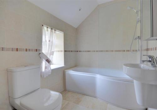 ein weißes Badezimmer mit einer Badewanne, einem WC und einem Waschbecken in der Unterkunft Cheyne Cottage in Hawsker
