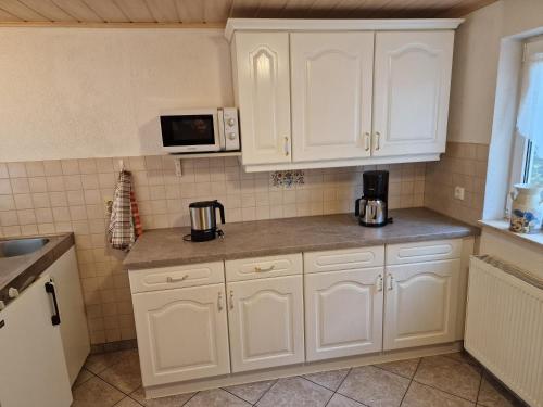 a kitchen with white cabinets and a microwave at Ferienhaus Gampe in Klingenthal