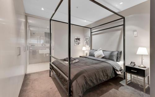 Opulent Level 25 Condo with Breathtaking Views في ملبورن: غرفة نوم مع سرير مظلة ودش