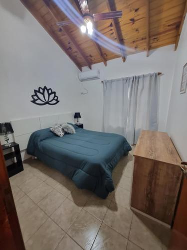 1 dormitorio con cama azul y techo de madera en Dunas del Sur II en Villa Gesell