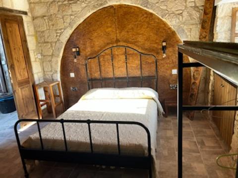 Cama en habitación con pared de piedra en Romanos Villa, en Pafos