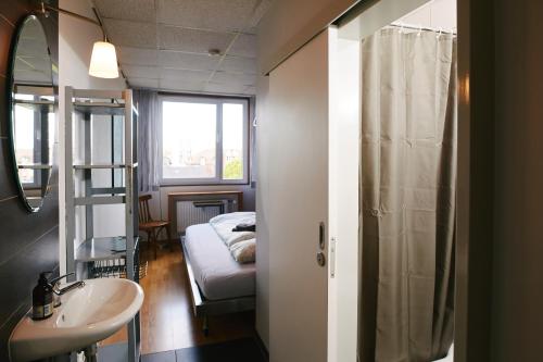 uma casa de banho com um lavatório e uma cama num quarto em Sleep Station Hostel em Münster