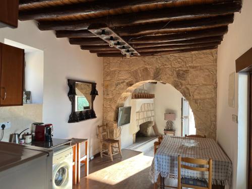 a kitchen and dining room with a table and a stone wall at Romanos Villa in Paphos