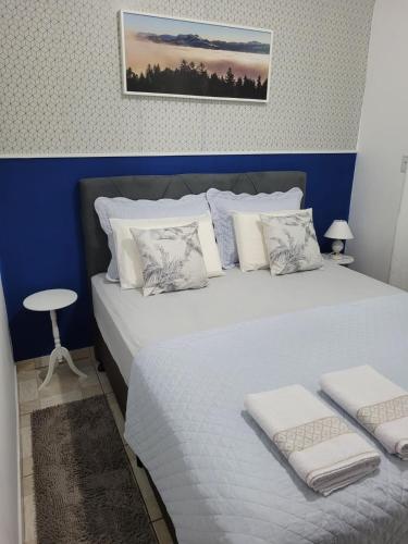 um quarto com uma cama grande com lençóis brancos e almofadas em Apartamento Aconchego Azul Pomerode em Pomerode