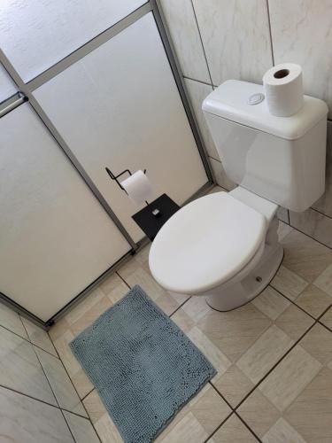 uma casa de banho com um WC, um chuveiro e um tapete. em Apartamento Aconchego Azul Pomerode em Pomerode