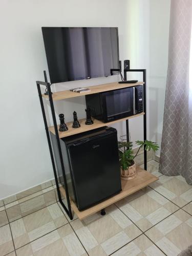 a tv on a stand with a microwave and a television at Apartamento Aconchego Azul Pomerode in Pomerode
