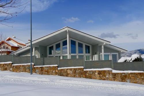 a house with a stone wall in the snow at Casa Nunki in Guadalix de la Sierra