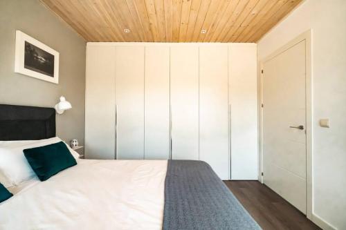 a bedroom with a white bed and a wooden ceiling at Casa Nunki in Guadalix de la Sierra