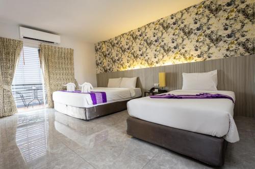 a hotel room with two beds and a wall mural at Embryo Hotel  in Pattaya Central