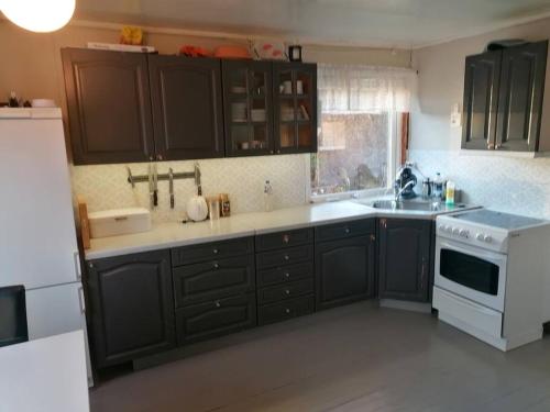 a kitchen with black cabinets and a white stove at Beautiful Lavangsnes, sea , private beach, boat. 