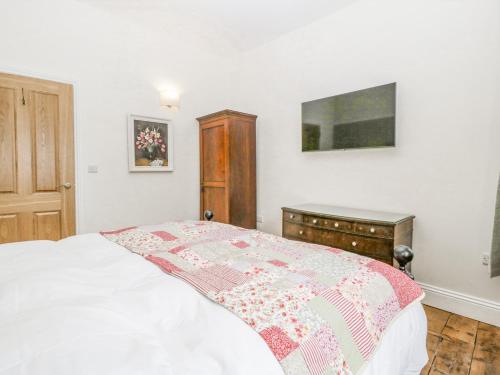 a bedroom with a white bed and a dresser and avertisement at Belle Vue in Hereford