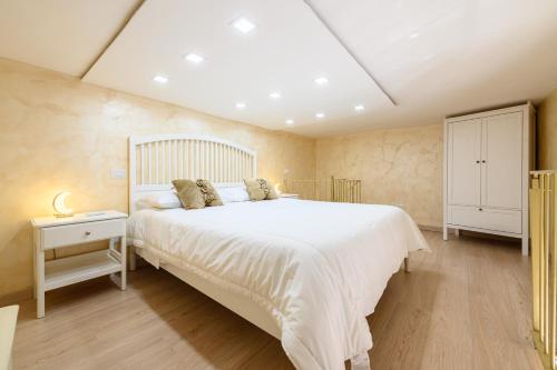 a bedroom with a large white bed and a white cabinet at La magnifica napoli apartments gold house in Naples