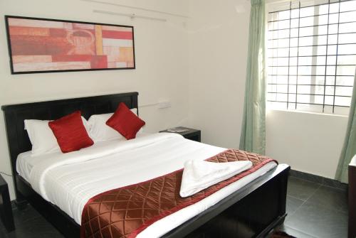 a bedroom with a large bed with red pillows at The Altruist Business Stays, Manayata Tech Park in Bengaluru