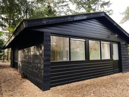 een zwarte cabine met ramen aan de zijkant bij Wellness Cabin Nulytø 24 in Rheezerveen