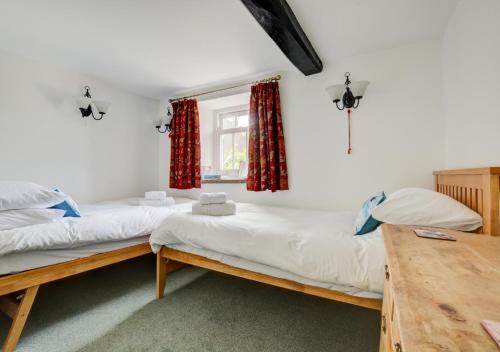 two beds in a room with a table and a window at Calverts Nook in Hawes