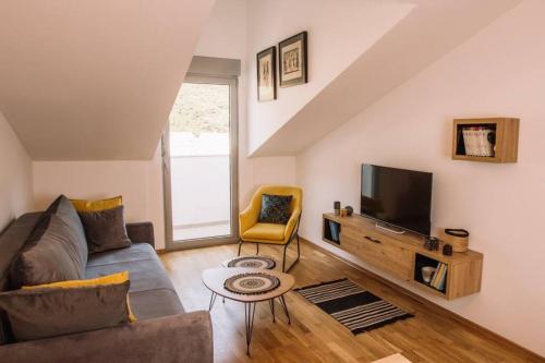 a living room with a couch and a tv at MT One-bedroom boho apartment, Budva in Budva