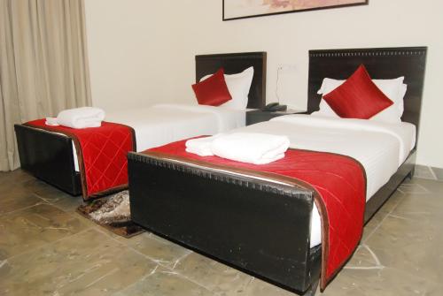 two beds with red and white pillows in a room at The Altruist Business Stays, Manayata Tech Park in Bengaluru