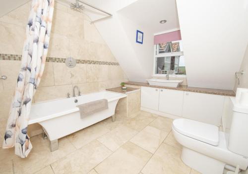 a bathroom with a tub and a toilet and a sink at Call Out Cottage in Sledmere