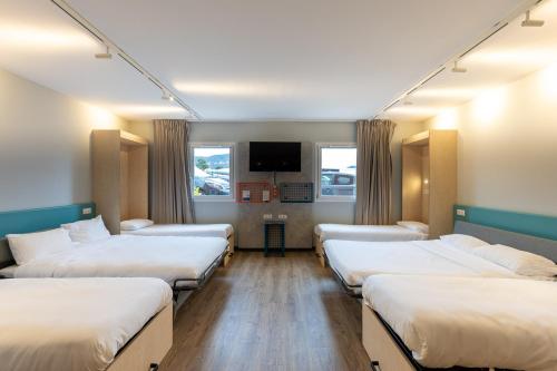 a hospital room with four beds and a flat screen tv at ibis Budget Millau Viaduc in Millau